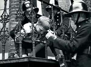 Print favourites Collection: Firefighter releasing boy with head stuck in railings LFB150
