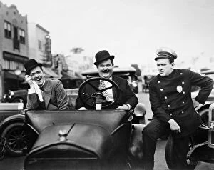 Street art portraits Collection: LAUREL AND HARDY, 1928. Stan Laurel, left, and Oliver Hardy with a police officer in the silent