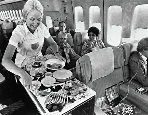 A Pan American flight attendant serves a meal to passengers on board. Photograph, c1975 A Pan American flight attendant serves a meal to passengers on board. Photograph, c1975