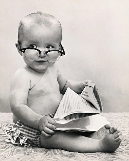 Baby wearing eyeglasses and holding paper Baby wearing eyeglasses and holding paper