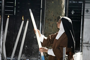 Nun lighting a candle at the Lourdes shrine Nun lighting a candle at the Lourdes shrine