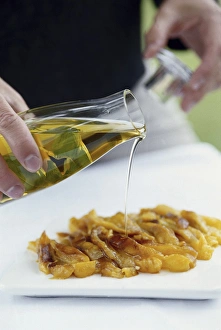 Pouring olive oil from glass serving bottle over roasted yellow peppers Pouring olive oil from glass serving bottle over roasted yellow peppers