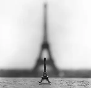 Prints of Black and white image of Eiffel Tower figurine sits on ledge in Trocadero, with silhouette of real Eiffel Tower rising behind it International Architecture Prints: Large and Small Black and White Eiffel Tower Print