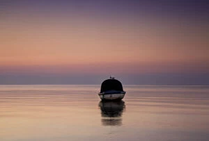 Victoria (VIC) Collection: Reflections of a single boat moored on the bay at sunrise in fog, South Werribee