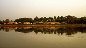 River Gambia at sunset with Tendaba settlement reflections on calm water during sunset River Gambia at sunset with Tendaba settlement reflections on calm water during sunset