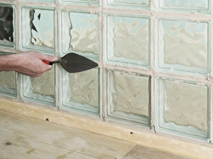 Adding grout to joints around a glass block with a trowel Adding grout to joints around a glass block with a trowel