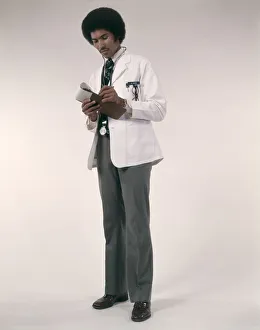 African-American Man Doctor Wearing White Coat And Stethoscope Writing Prescriptions African-American Man Doctor Wearing White Coat And Stethoscope Writing Prescriptions