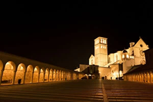 Arches along Piazza San Francesco at night with Basilica of San Francesco d Assisi in the background