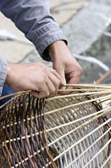 A basket weaver sitting on the street and weaving a basket, Brittany, France, Europe A basket weaver sitting on the street and weaving a basket, Brittany, France, Europe
