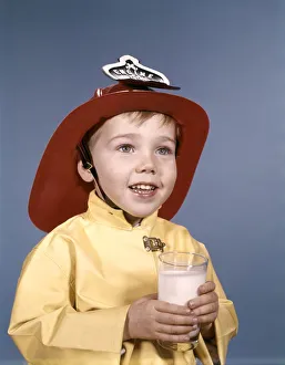 Boy in fireman costume, holding a glass of milk Boy in fireman costume, holding a glass of milk