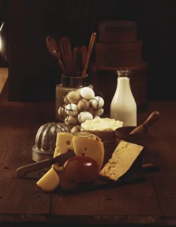 Cheese on wooden board with milk and eggs in background Cheese on wooden board with milk and eggs in background