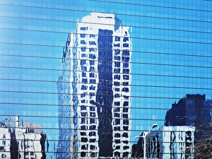 Cityscape reflected in glass facade of building
