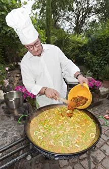 Cook preparing a paella, a Spanish rice dish, adding peppers, series, no. 2 Cook preparing a paella, a Spanish rice dish, adding peppers, series, no. 2