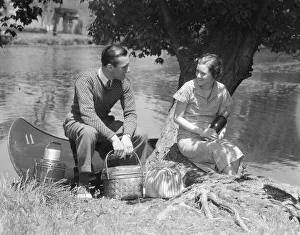 Couple Young Man Woman Smiling In Front Of Canoe With Picnic Basket Thermos Man Sweater Couple Young Man Woman Smiling In Front Of Canoe With Picnic Basket Thermos Man Sweater