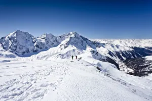 Cross-country skiers descending Hintere Schoentaufspitze Mountain, Solda, looking towards Koenigsspitze Mountain Cross-country skiers descending Hintere Schoentaufspitze Mountain, Solda, looking towards Koenigsspitze Mountain