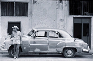 Cuban man leaning against car smoking cigar (B&W) Cuban man leaning against car smoking cigar (B&W)