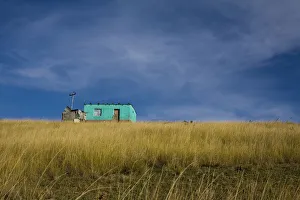 Distant view of a small traditional 'flat' house under blue sky and surrounded by golden wavy grass , Coffee Bay, Eastern Cape province, South Africa Distant view of a small traditional 'flat' house under blue sky and surrounded by golden wavy grass , Coffee Bay, Eastern Cape province, South Africa
