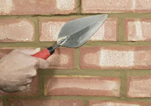 Filling areas of brick wall with mortar using a trowel, close up Filling areas of brick wall with mortar using a trowel, close up