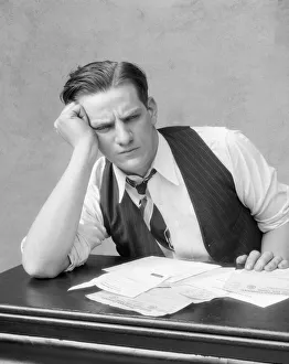 Frowning Man With Dress Shirt Open At The Collar, Tie & Unbuttoned Vest Sitting At Desk Frowning Man With Dress Shirt Open At The Collar, Tie & Unbuttoned Vest Sitting At Desk