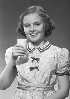 Girl (12-13) posing with glass of milk, (B&W), portrait Girl (12-13) posing with glass of milk, (B&W), portrait