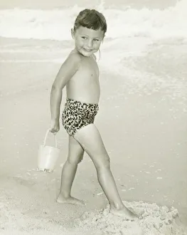 Girl (6-7) standing on beach, smiling, (B&W) Girl (6-7) standing on beach, smiling, (B&W)
