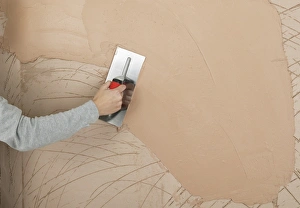Hand applying plaster to a wall with a trowel Hand applying plaster to a wall with a trowel