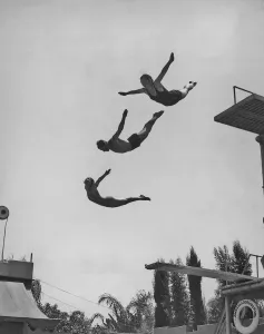 Prints of Two women and a man in mid air after using a diving board at the Ambassador Lido pool in Los Angeles, California circa 1940 s. (Photo by Keystone View/FPG/Getty Images) Black and White Images Capturing the Essence of Mid-20th Century: Diving Board Print, 1940s Ambassador Lido Pool
