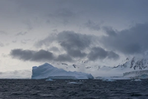 Iceberg in a fjord with mountain scenery and a cloudy sky, Gerlache Strait, Antarctic Peninsula, Antarctica Iceberg in a fjord with mountain scenery and a cloudy sky, Gerlache Strait, Antarctic Peninsula, Antarctica