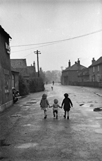 Its A Lonely Road; Three children walk hand in hand down the main street of the village Its A Lonely Road; Three children walk hand in hand down the main street of the village