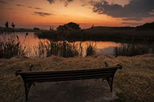 Lonesome bench landscape at sunset on the shore of a remote farm lake, Magaliesburg, Gauteng Province, South Africa Lonesome bench landscape at sunset on the shore of a remote farm lake, Magaliesburg, Gauteng Province, South Africa