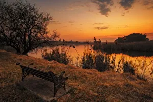 Lonesome park bench at sunset on the shores of a remote farm lake near Magaliesburg, Gauteng Province, South Africa Lonesome park bench at sunset on the shores of a remote farm lake near Magaliesburg, Gauteng Province, South Africa