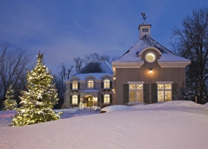 Luxurious residential cottage style home with illuminated evergreen trees at dusk in winter, Quebec, Canada Luxurious residential cottage style home with illuminated evergreen trees at dusk in winter, Quebec, Canada
