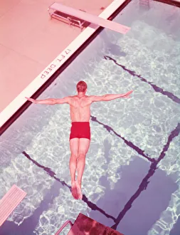 Man diving into swimming pool, overhead view. (Photo by H Man diving into swimming pool, overhead view. (Photo by H