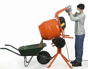 Man emptying contents of cement mixer into a wheelbarrow Man emptying contents of cement mixer into a wheelbarrow