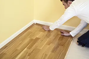 Man holding piece of quadrant on laminate flooring Man holding piece of quadrant on laminate flooring