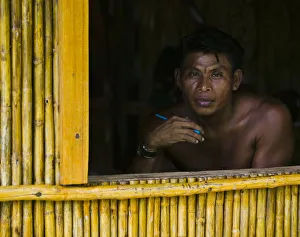 Man looking out window of bamboo hut, portrait Man looking out window of bamboo hut, portrait