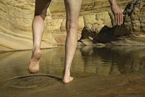Man stepping into pool of water in sandstone, low section Man stepping into pool of water in sandstone, low section