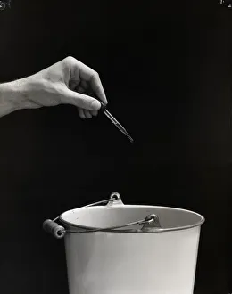 Man's hand squeezing eyedropper over bucket. (Photo by H Man's hand squeezing eyedropper over bucket. (Photo by H