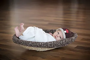 Newborn baby, 3 weeks, wearing a hat, lying in a basket Newborn baby, 3 weeks, wearing a hat, lying in a basket