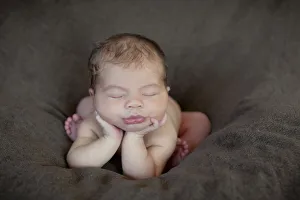 Newborn baby, five days, asleep with head propped up on hands Newborn baby, five days, asleep with head propped up on hands