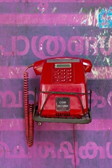 Old red telephone against a wall with pink Malayalam script, Kerala, India Old red telephone against a wall with pink Malayalam script, Kerala, India