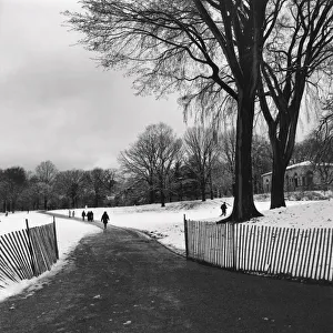 People walking on a path through a snow covered park People walking on a path through a snow covered park
