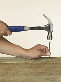 Person hitting nail into wood with hammer Person hitting nail into wood with hammer