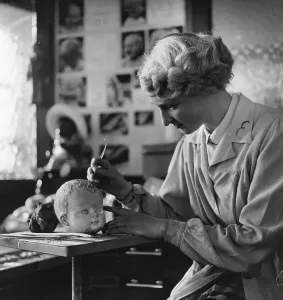A worker paints a Patsy doll head at the Cascelloid factory