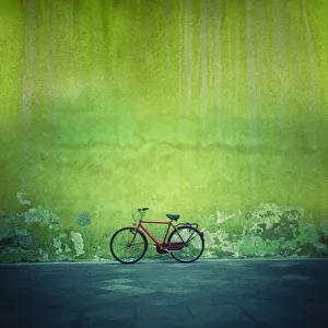 Red vintage bike against a green flaking plaster wall Red vintage bike against a green flaking plaster wall