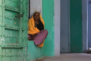 Senior woman sitting in front door of home, smiling, portrait Senior woman sitting in front door of home, smiling, portrait