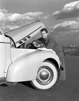 Smiling man in coveralls under hood of sedan, holding monkey wrench Smiling man in coveralls under hood of sedan, holding monkey wrench