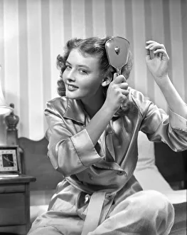 Smiling teenage girl in bathrobe brushing hair in the morning Smiling teenage girl in bathrobe brushing hair in the morning