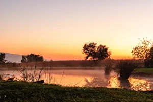 The sun rises over a small dam in the high veld winter landscape near Hartebeespoort The sun rises over a small dam in the high veld winter landscape near Hartebeespoort