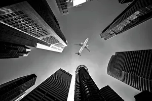 Tall city buildings and a plane flying overhead Tall city buildings and a plane flying overhead